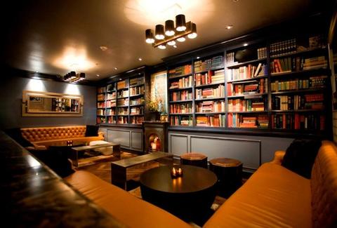 Bench seating ,small round tables and wall of books