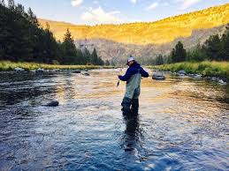 fisherman in water with mountains surrounding him